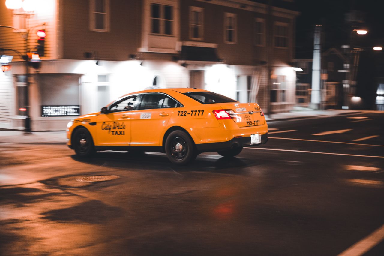 Dynamic yellow taxi captured in motion on a city street at night.