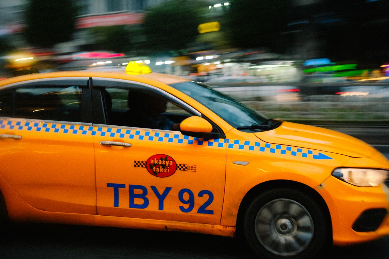services-03 A motion blur shot of a yellow taxi speeding through a city street at night, conveying urban hustle.