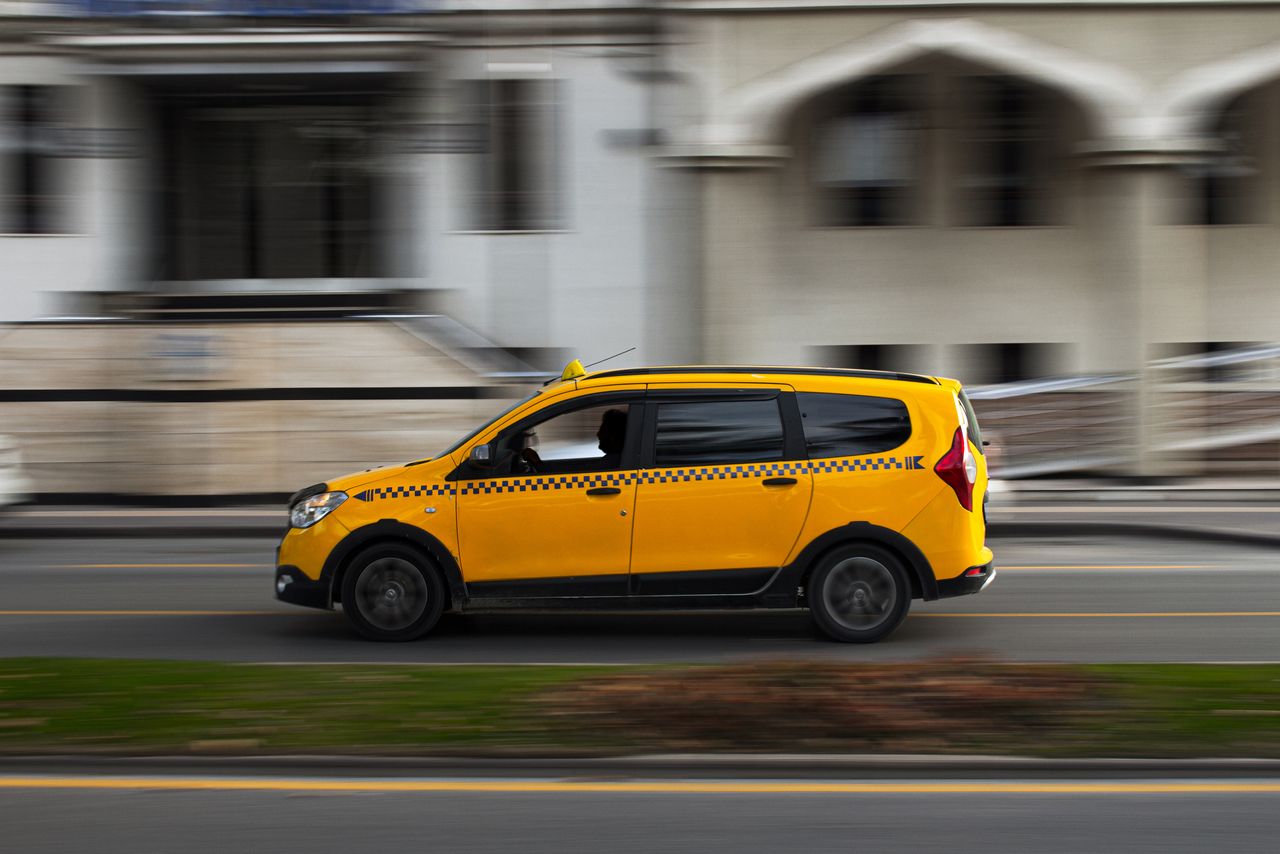 hero-img-02 A yellow taxi in motion on a city road, showcasing dynamic urban travel.