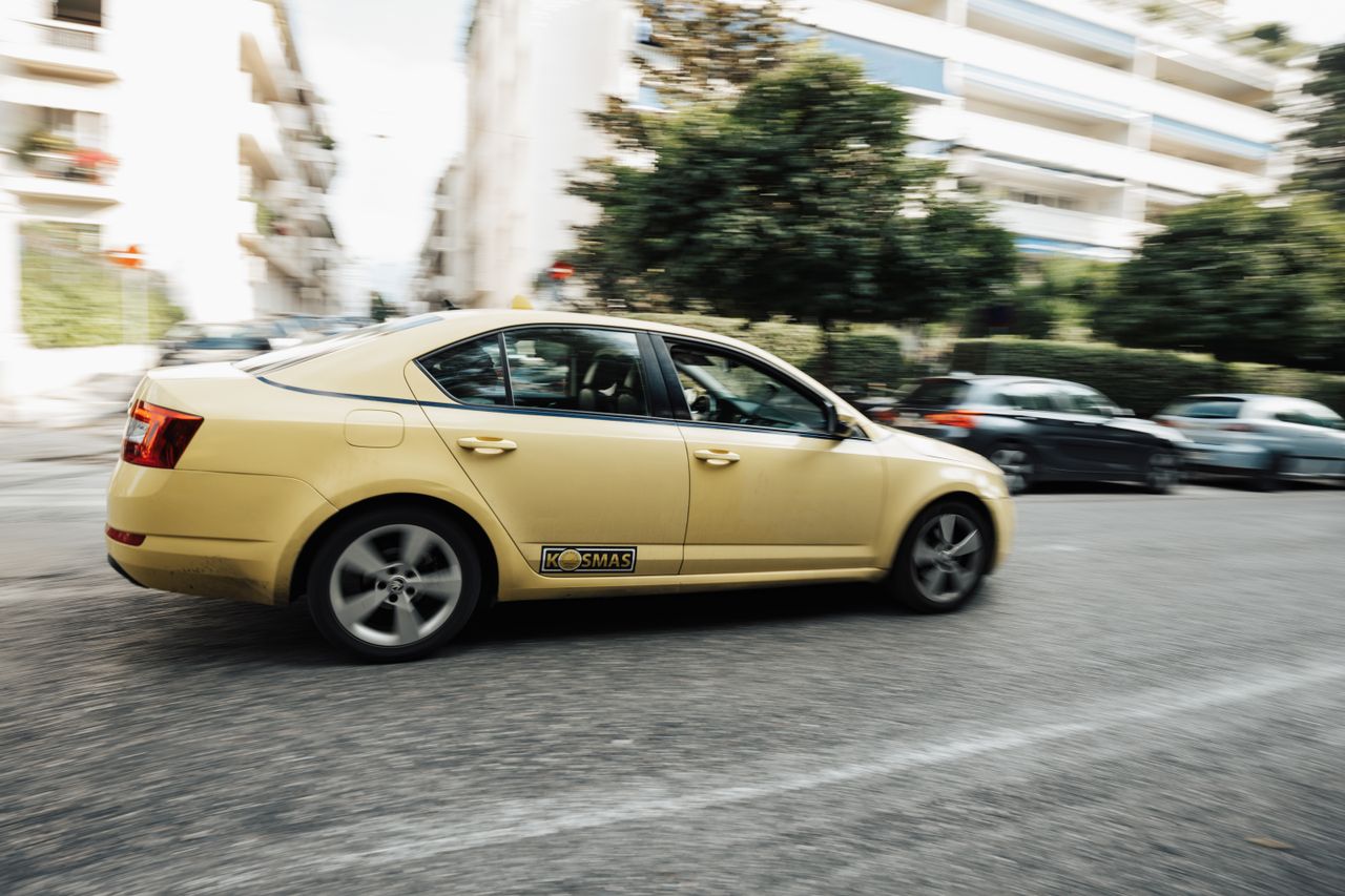 about-01 A yellow taxi speeds down a city street, capturing the essence of urban life and transportation.