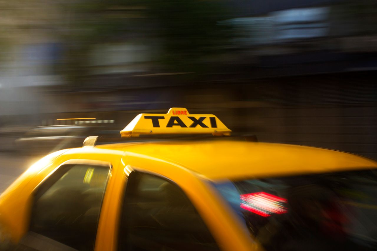 about-02 A vibrant yellow taxi with motion blur speeding through a nighttime city street.