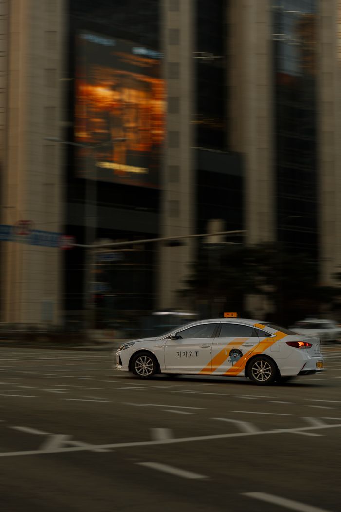 gallery-6 A taxi speeds through a bustling city intersection, capturing the essence of urban life.