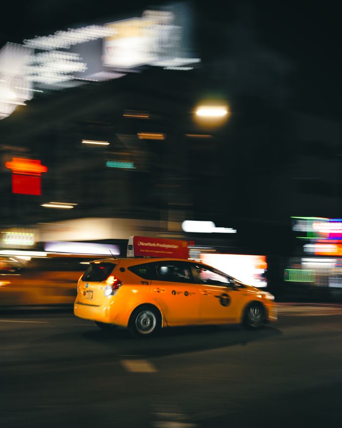 services-02 Blurred motion of a speeding yellow taxi on a New York City street at night.