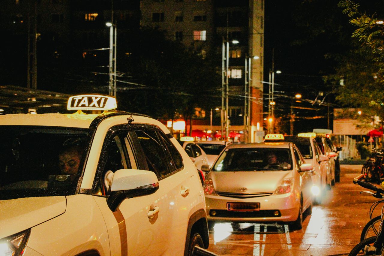 ours-journey Taxis lined up under streetlights in Salzburg, Austria, captured at night.