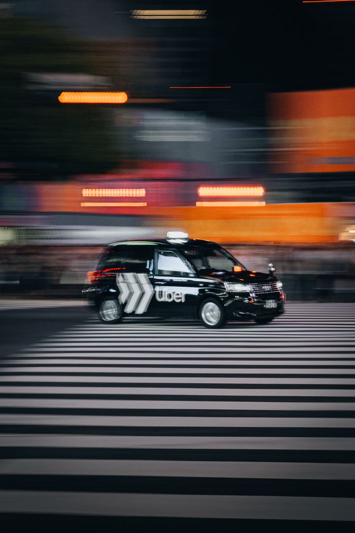 services-01 Blurred taxi speeds across a city crosswalk, capturing urban motion and nightlife energy.