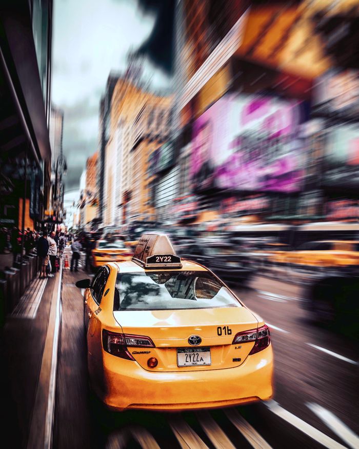 services-img Long exposure image capturing the vibrant energy of New York City with a focused yellow taxi and blurred motion all around.
